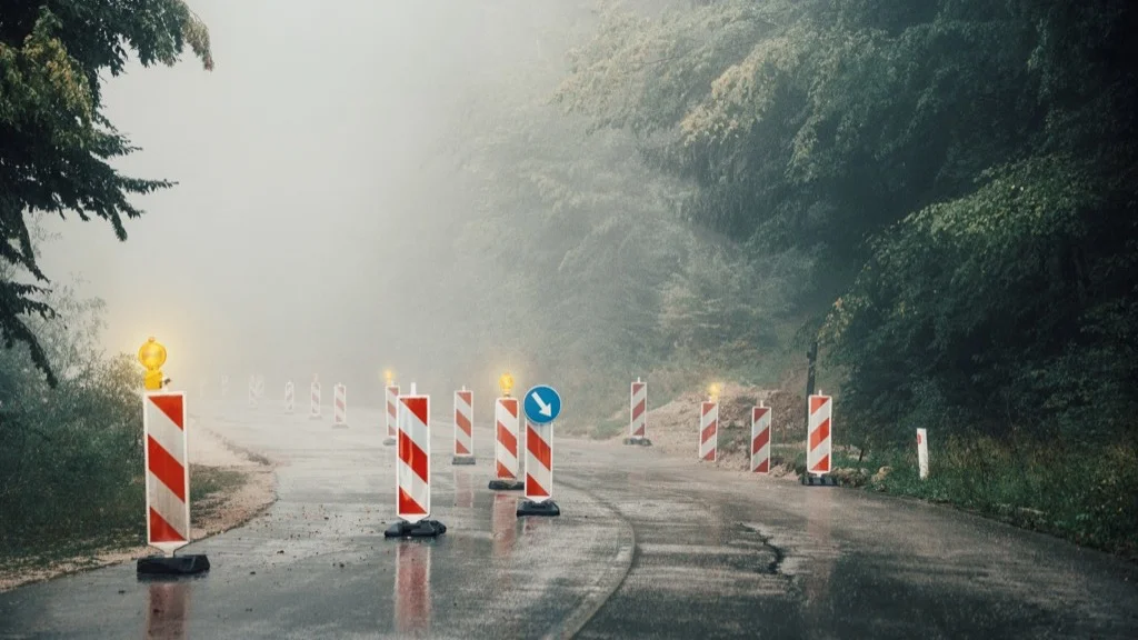 Foggy road with construction barriers and warning signs, representing obstacles and quality challenges
