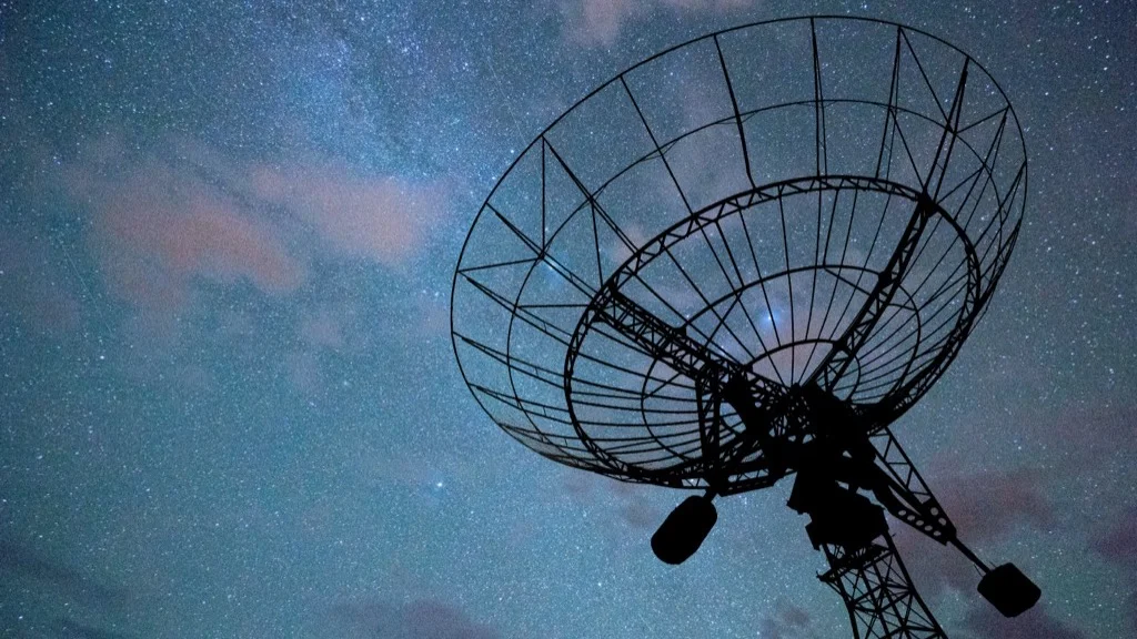 Satellite dish against starry night sky, representing early detection and monitoring systems